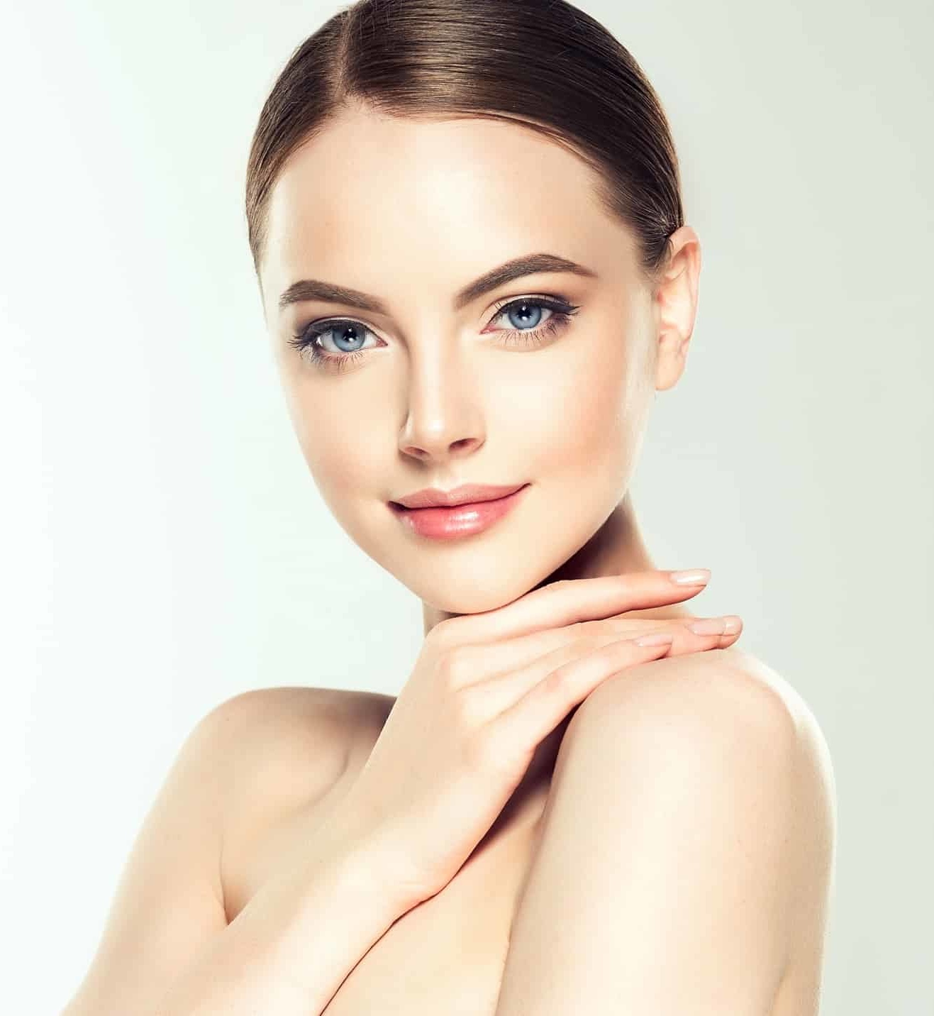 Gorgeous, young woman with clean, fresh skin is touching own face. Light smile on the perfect face.