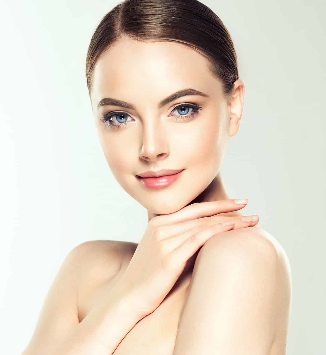 Gorgeous, young woman with clean, fresh skin is touching own face. Light smile on the perfect face. Gorgeous, young woman with clean, fresh skin is touching own face. Light smile on the perfect face.