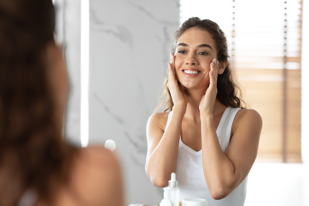 Woman looking in the mirror after using retinol skincare in Austin, TX