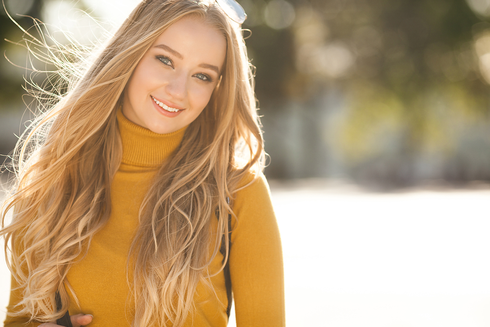 Woman in fall attire smiling with clear skin from dermaplaning in Austin, TX