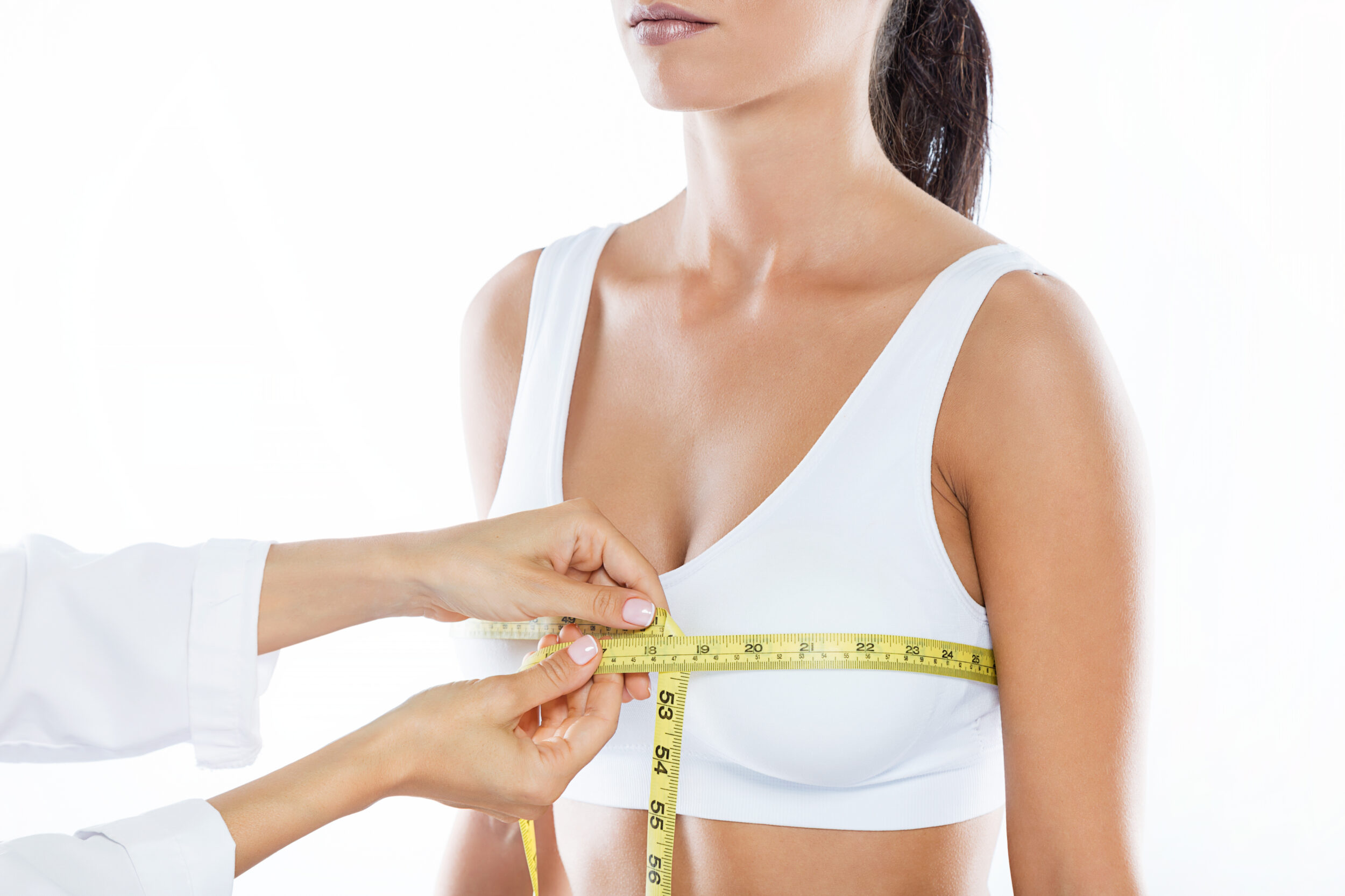 Surgeon measuring woman's breasts for breast reduction surgery in Austin, TX